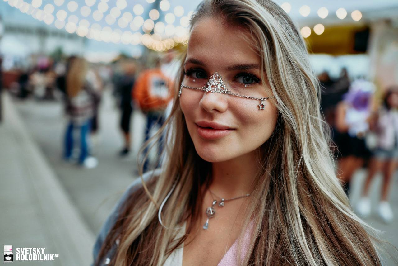 Portrait of woman with blonde hair wearing silver facechain with triangular design